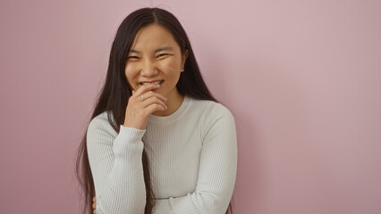 Woman smiling confidently against an isolated pink background, illustrating asian beauty and style...