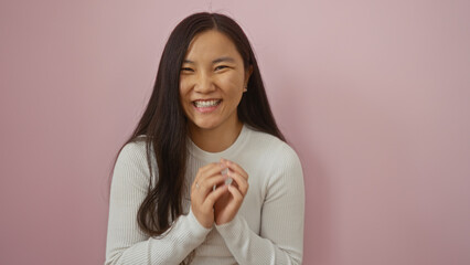 Young chinese woman smiling beautifully against an isolated pink background, showcasing natural...