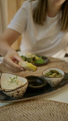 Woman enjoying mediterranean appetizers indoors at a restaurant showcasing rich food textures and casual dining atmosphere.