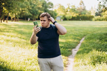 Sad blonde man got lost and could not find an internet connection on phone on the nature background. Male explorer looking for connection to the internet or using gps navigator app on phone