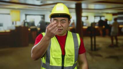 Man wearing construction outfit in hotel lobby with determined look amidst busy indoor environment