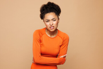 Young ill strong fitness trainer sporty woman wear orange clothes spend time in home gym put hands...