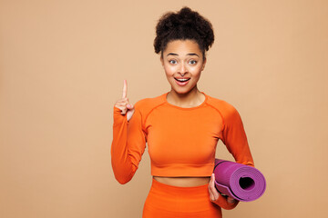 Young fitness trainer instructor sporty woman sportswoman wears orange clothes spend time in home...