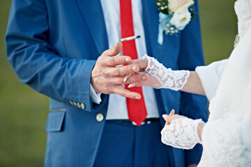 A man and woman are getting married and the man is putting a ring on the woman's finger
