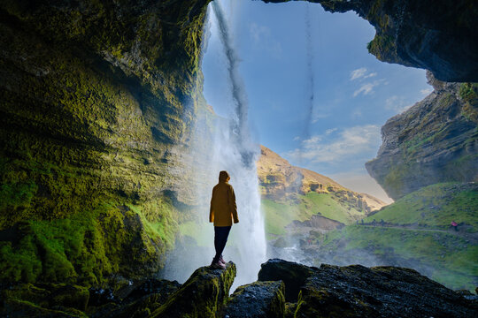 View from inside Kvernufoss waterfall showcasing a person exploring Icelandic nature - Powered by Adobe