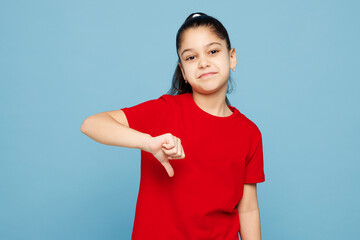 Little disappointed kid girl 8-9 years old wearing red t-shirt showing thumb down dislike gesture...