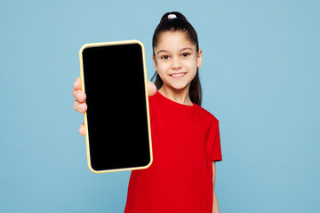 Little kid girl 8-9 years old wear red t-shirt hold in hand use mobile cell phone with blank screen...