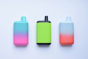 Several multi-colored electronic cigarettes lie on a light table.