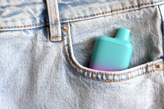 One multi-colored electronic cigarette in the pocket of jeans. Vape with nicotine.