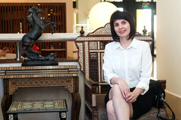 Elegant Woman in White Blouse Relaxing Cozy Hotel Lobby – Stylish and Inviting Atmosphere.