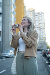 Fototapeta premium A young woman photographer taking photos in the city with a retro point-and-shoot camera