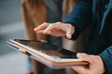 Hands navigate and interact with a tablet device outdoors, highlighting modern technological...