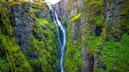 Glymur waterfall cascading down lush green cliffs in Icelands scenic landscape