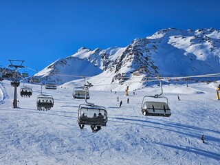 A ski slope with a lot of people on it and a lot of ski lifts. The ski lift is in the middle of the...