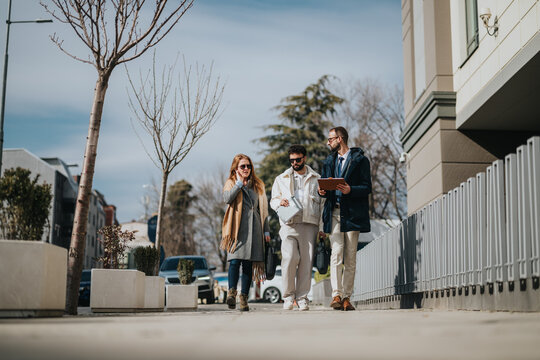 A cheerful group of coworkers walking along a street during a sunny day, engaging in a collaborative conversation.