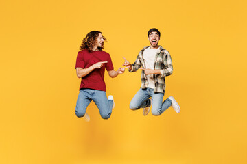 Full body young exultant two friends buddies men wear casual clothes together jump high point index...