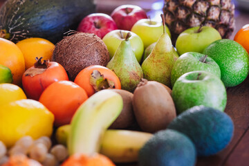 Vibrant close-up of a diverse selection of fresh tropical and seasonal fruits, including bananas, oranges, apples,  pears, grapes, avocados, blackberries, and grapefruit. Healthy eating concept