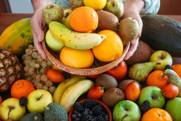 Vibrant close-up of a diverse selection of fresh tropical and seasonal fruits, including bananas, oranges, apples,  pears, grapes, avocados, blackberries, and grapefruit. Healthy eating concept