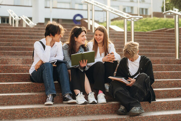 Fototapeta premium Under sunlight, sitting. Group of students are near university together