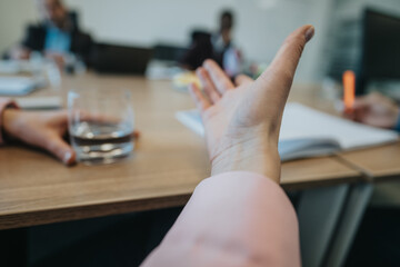 A detailed view of a hand gesturing during a collaborative business meeting, indicating discussion...