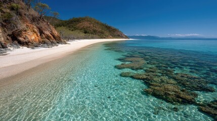 Island coastline with white sand beach and coral reef visible through clear water