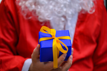 Santa Claus in red suit with beard giving Christmas gift on Christmas, magic of Christmas,