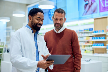 Pharmacist Assisting Customer with Tablet in Modern Pharmacy Interior
