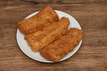 Pollock fillets fried in golden breadcrumbs, lying on a plate, crispy fish
