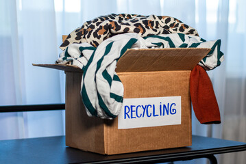 Cardboard box full of clothes labeled Recycling. Concept of sustainable fashion and responsible...