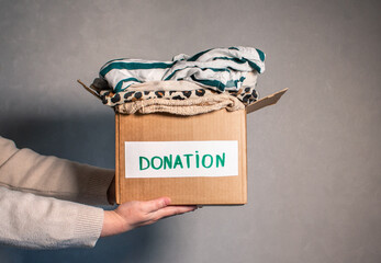 Woman folding clothes and placing them into donation box. Concept of charity and wardrobe...
