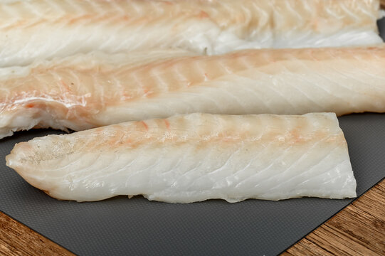 Fresh fish, cod loin on a chopping board close-up