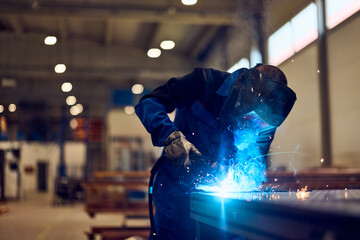 Industrial Worker Welding Metal in a Factory Workshop, Bright Sparks Flying