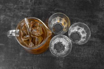 An overhead shot of a glass jug full of iced tea, a refreshing treat on a hot day