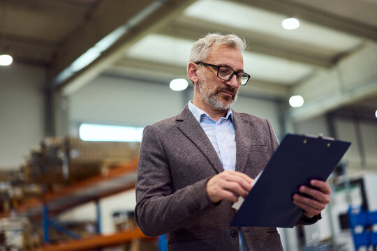 Professional Manager Reviewing Documents in a Modern Industrial Facility