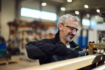 Smiling Worker Controlling Equipment in an Industrial Workshop Environment