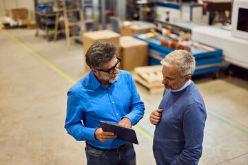 Two Professionals Discussing Business Strategies in a Modern Warehouse Setting