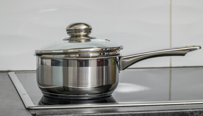 Cooking concept, a steel saucepan is standing on an induction cooker, something is cooking