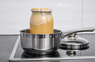 Decrystallization of bee honey, a jar of honey is standing in a pot