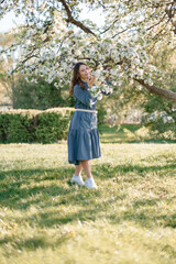 A young woman enjoying a blooming garden. The concept of youth, love, fashion, and lifestyle.