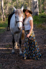 A white horse with a woman wearing an Australian outback hat