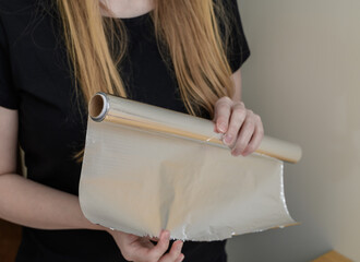 Woman using aluminum foil for baking in the kitchen