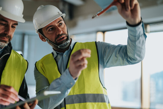 Two professionals in safety gear discussing plans and tasks during the construction phase of a building project, emphasizing teamwork, precision, and expertise.