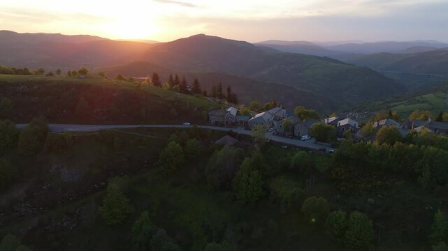 Aerial sunset view of O Cebreiro village with the sun setting behind Galician mountains. Iconic spot on the Camino de Santiago with warm light and scenic, spiritual atmosphere.