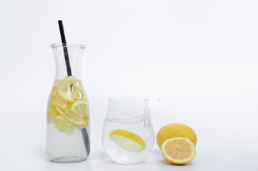 A glass of water with a slice of lemon on a light background, a summer refreshment to cool down
