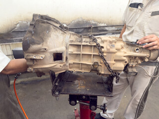 A team of expert technicians is performing maintenance on a complex car transmission system.