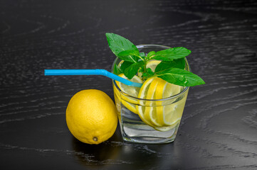 Water with lemon and mint in a glass on the table