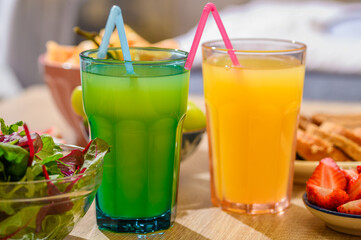Colorful healthy smoothies in tall glasses with straws and fresh fruit next to them