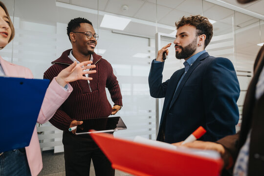 A group of diverse business professionals in a modern office engaged in conversation, sharing ideas, and working collaboratively. A casual atmosphere fostering creativity and teamwork.