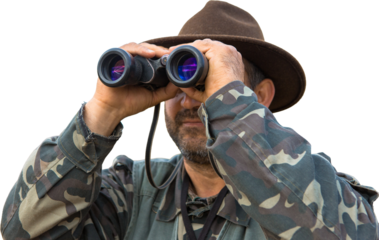 A hunter in a hat with binoculars looks out for prey 