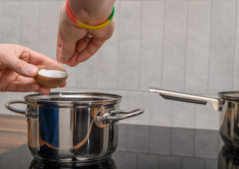 Table salt added to the pot, salting cooking food close up